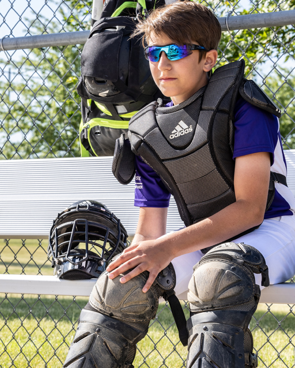 boy from the back holding a pair of cleats by the heel